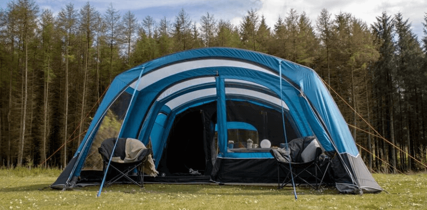 A UK camping tent pitched on grass with hills in the background under grey British sky